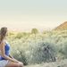A woman in casual attire sits peacefully, enjoying a scenic outdoor view of nature.